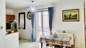 A dining area with a table set for four, a chandelier, a clock, and a painting on the wall. - Vacation home - Tourist rental "Belvedere House Holiday Syracuse Ortigia" (Siracusa)