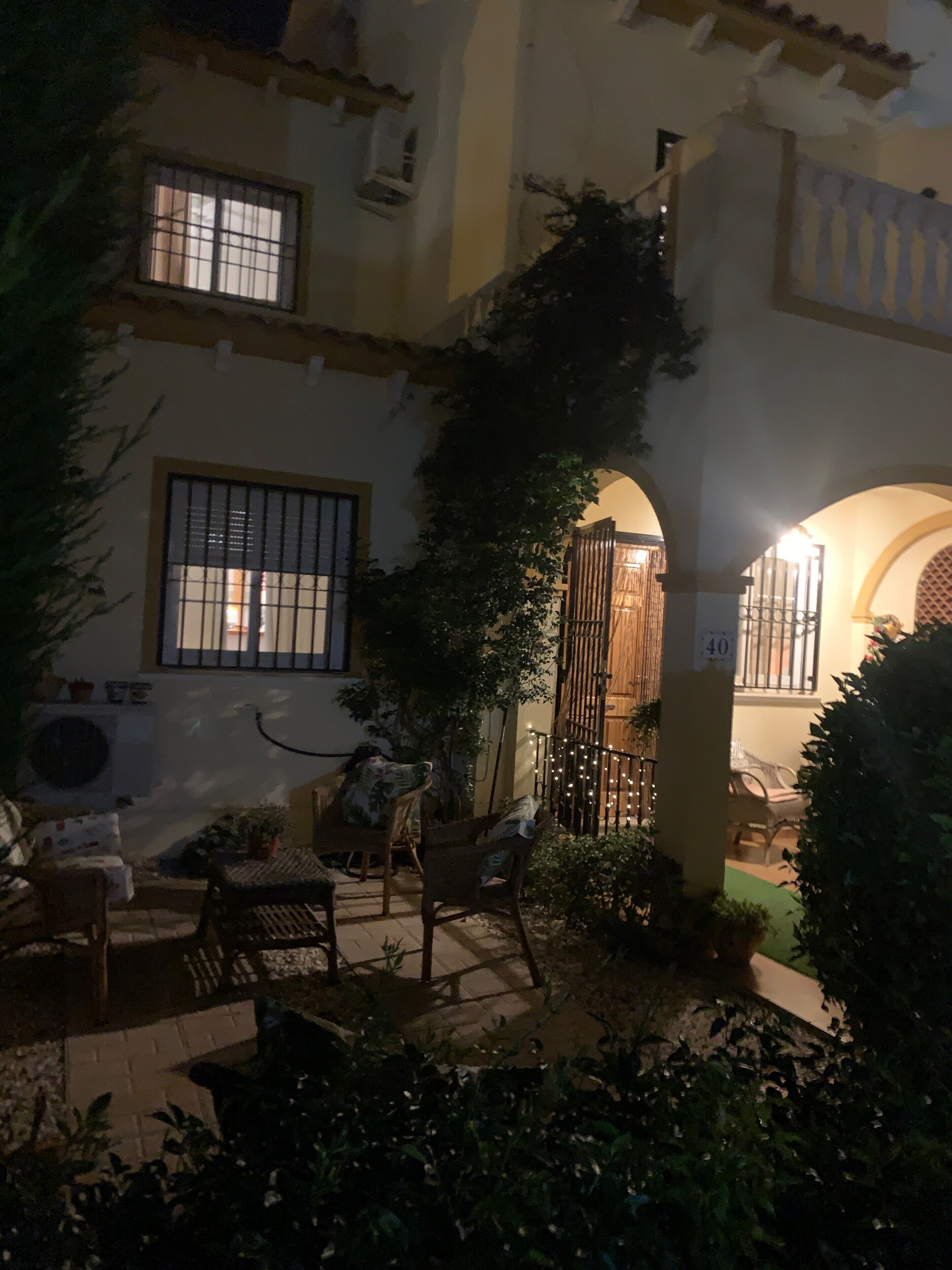 A courtyard with a seating area, a gate, and a building with barred windows.