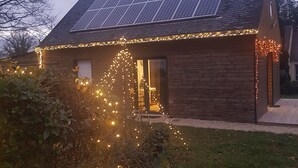 A house with solar panels, a wooden exterior, and string lights.