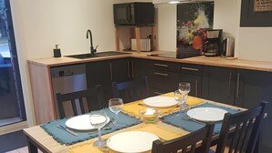 A modern kitchen with a dining area, featuring a built-in dishwasher, a microwave, and a coffee maker.