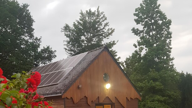 A wooden cabin with a gravel driveway and a patio area.
