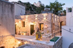 A stone building with a balcony, a table, and a chair.