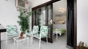 A room with a sliding glass door leading to a kitchen, a white air conditioning unit, a potted plant, and a small table with a statue. - Vacation Studio 'Loft Guanapay 1' with Private Terrace, Wi-Fi, and Air Conditioning (Arona)