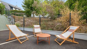 An outdoor seating area with two lounge chairs and a small table, surrounded by a metal fence and vegetation. - Apartment 'Appartement Centre - La Gacilly' with Wi-Fi (La Gacilly)