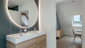 Un baño moderno con tocador de doble lavabo, un espejo grande y un mueble de madera.
