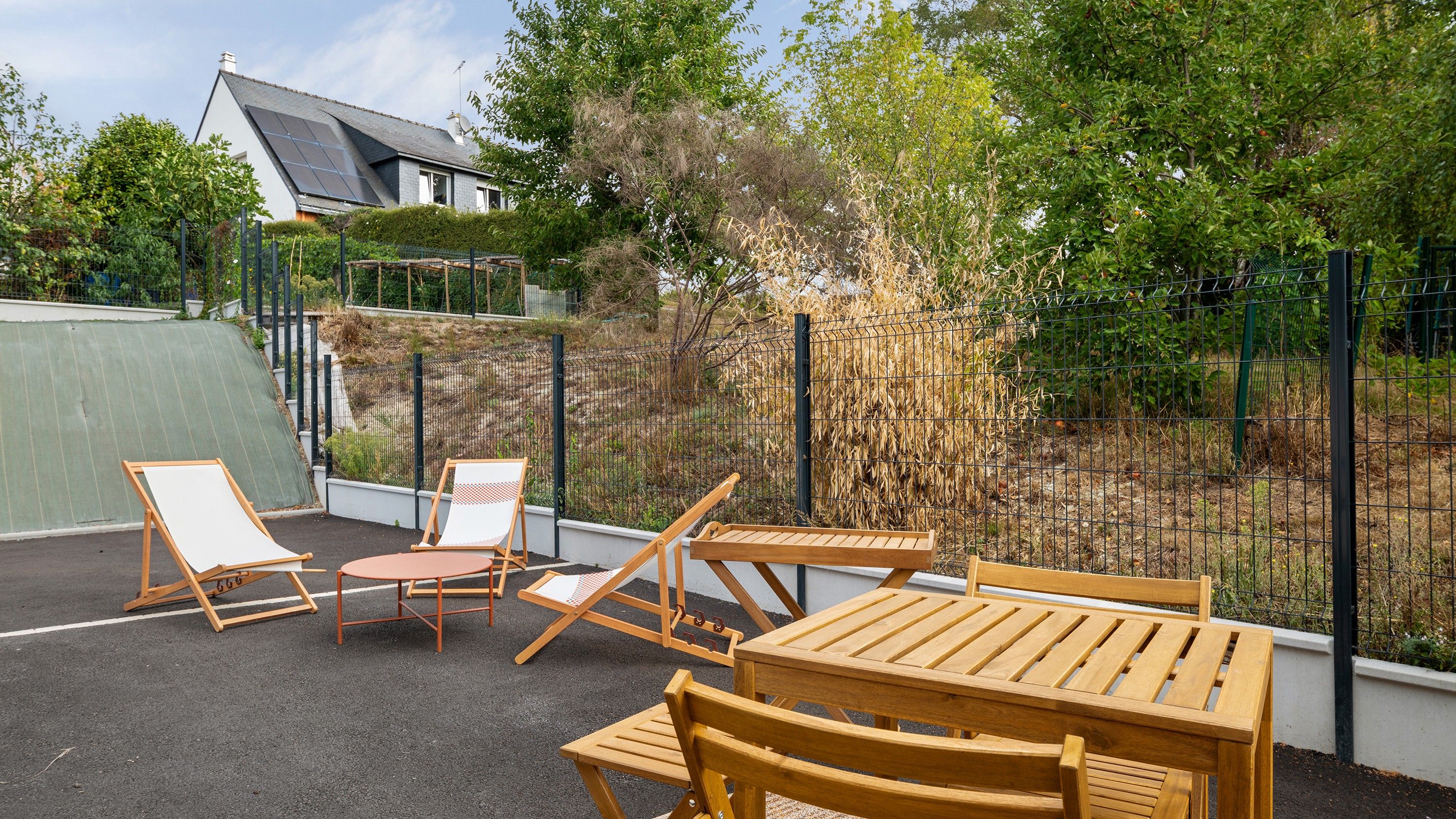 An outdoor seating area with wooden furniture and a metal fence.