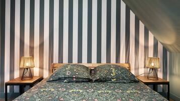 Ein Schlafzimmer mit einer gestreiften Wand, einem hölzernen Bett und zwei Nachttischlampen.