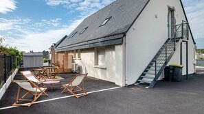 A building with a sloped roof, a staircase, and outdoor seating with tables and chairs. - Apartment 'Appartement Centre - La Gacilly' with Wi-Fi (La Gacilly)