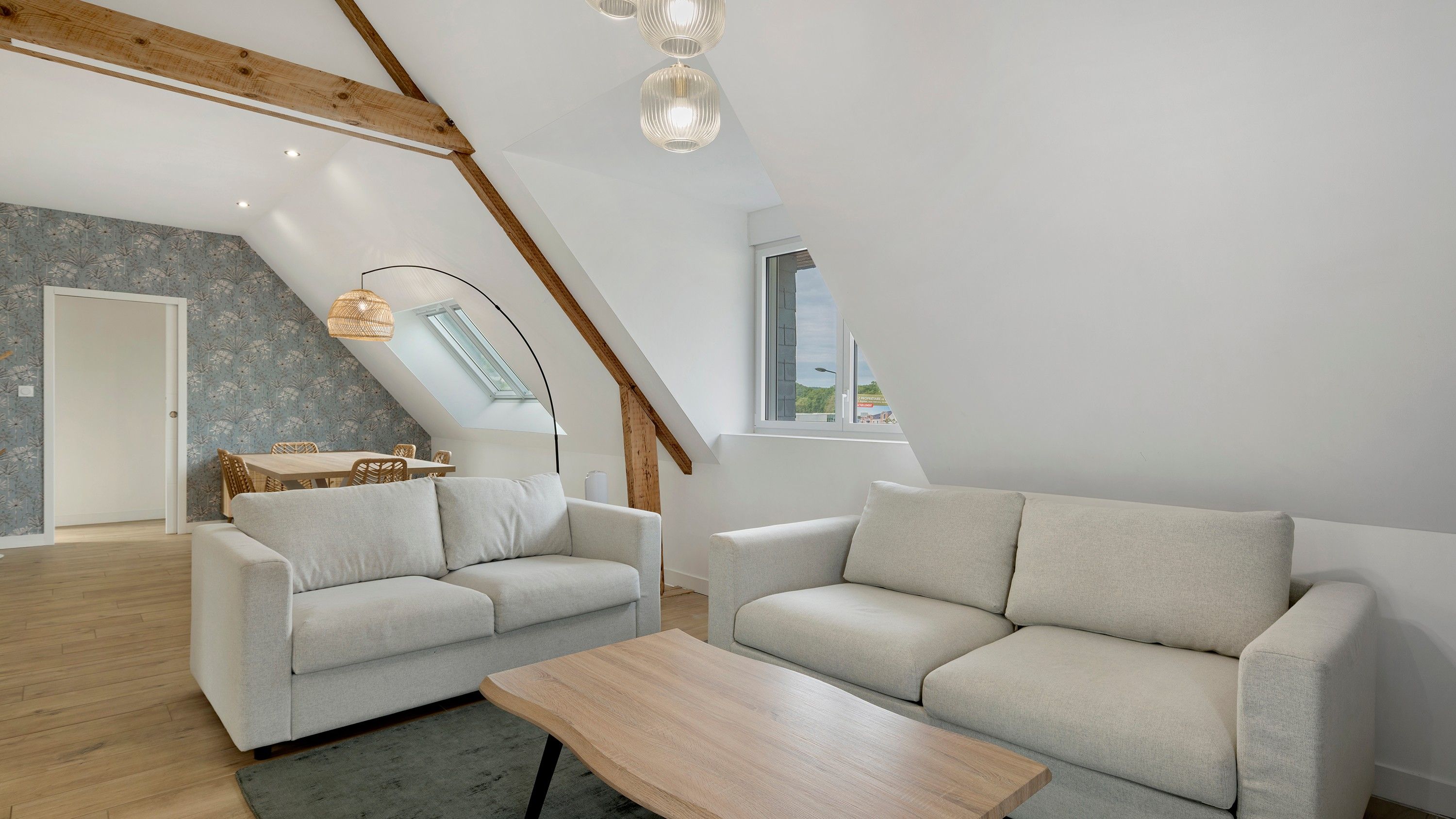 Ein stilvolles Loft mit hohen Decken, freiliegenden Holzbalken, einem Essbereich und einem Oberlicht.