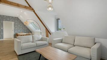 Ein stilvolles Loft mit hohen Decken, freiliegenden Holzbalken, einem Essbereich und einem Oberlicht.