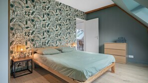 A bedroom with a bed, bedside lamps, a dresser, and a view of the outdoors. - Apartment 'Appartement Centre - La Gacilly' with Wi-Fi (La Gacilly)