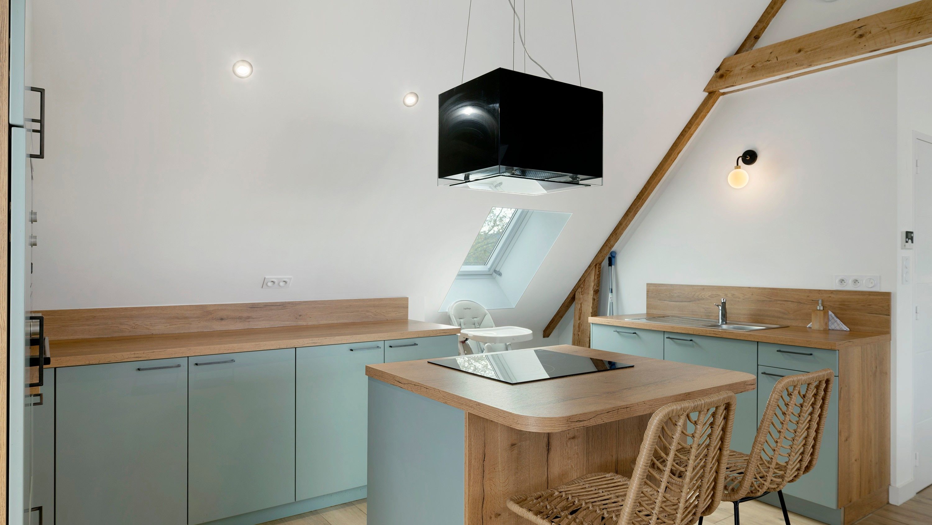 A modern kitchen with a central island, light blue cabinets, and a wooden countertop.