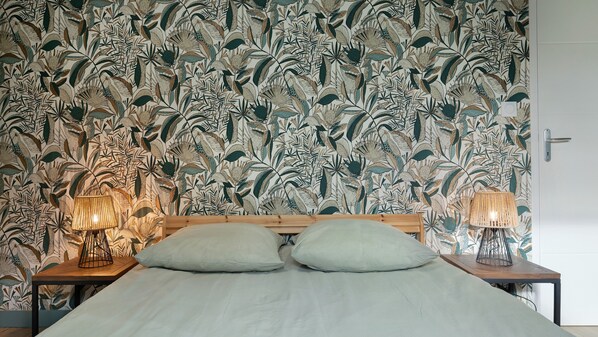 Un dormitorio con una cama, dos lámparas de noche y una pared con diseño de hojas.