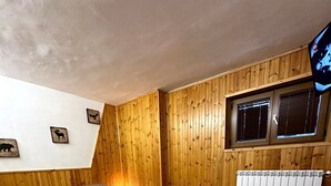 Une chambre à coucher avec un lit en bois, une table de chevet, un radiateur et une fenêtre avec des stores.