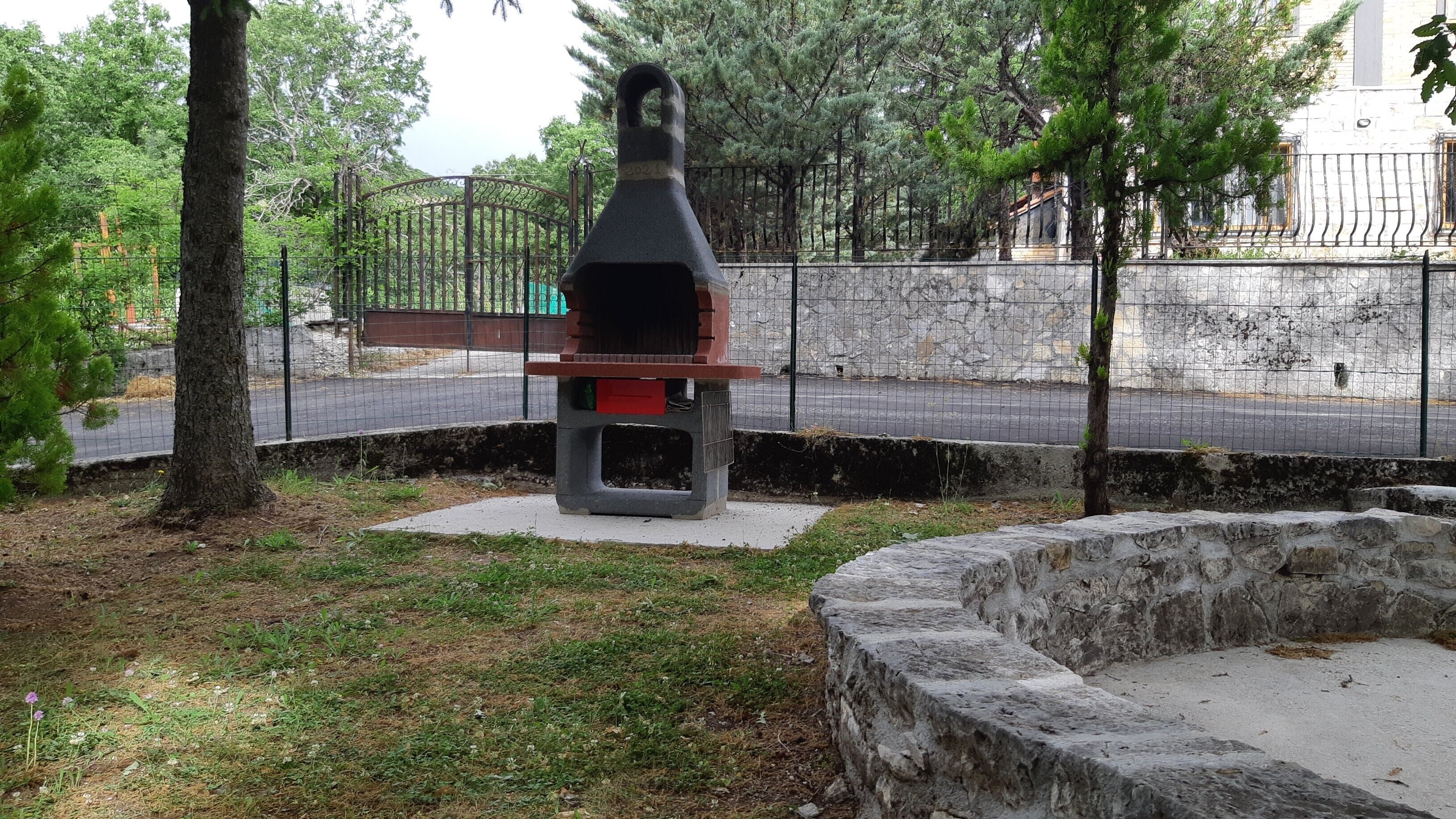 Un parc avec un banc en béton, une clôture en métal et des arbres.