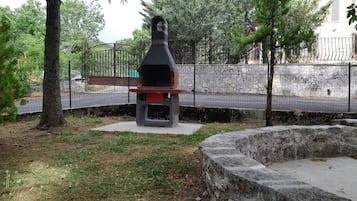 Un parc avec un banc en béton, une clôture en métal et des arbres.