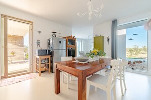 Una cucina moderna con un tavolo da pranzo in legno, sedie bianche e vista sull'esterno.