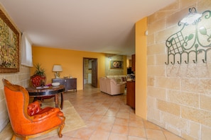 A living room with a sofa, a dining table with chairs, a decorative wall piece, and a door leading to another room.