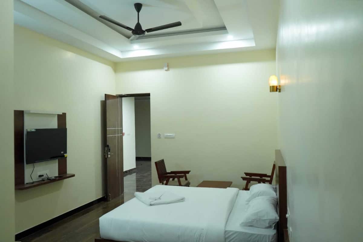 A hotel room with a bed, a desk, a chair, a television, and a ceiling fan.