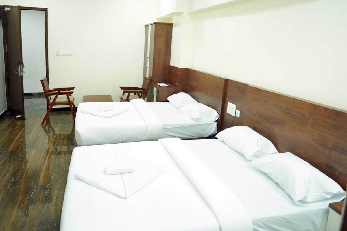 A hotel room with three single beds, wooden headboards, and a wooden chair.