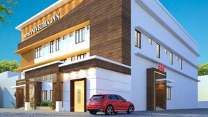 A modern hotel with a two-story structure, a visible bar, and a red car parked in front. - HOTEL NIVETHA INN (Coimbatore)