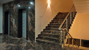 A marble-floored lobby with a staircase and elevator. - HOTEL NIVETHA INN (Coimbatore)