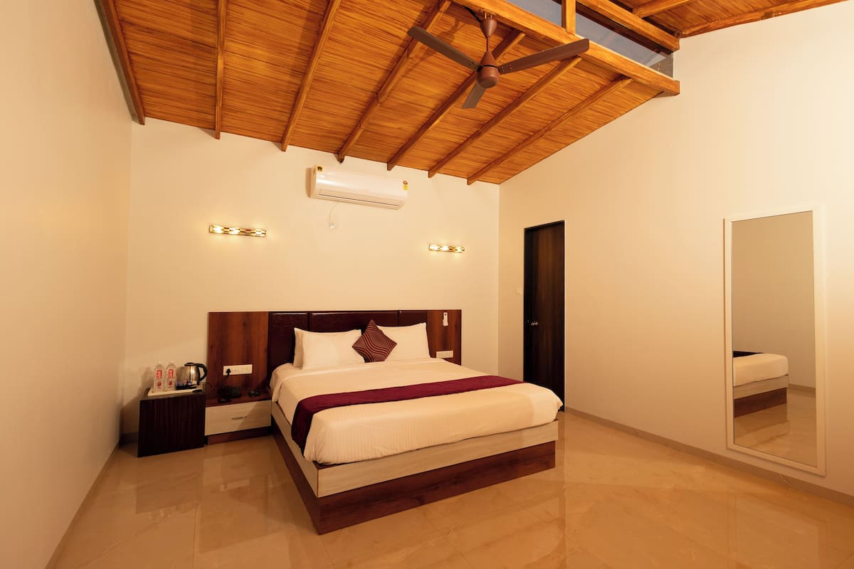 A modern bedroom with a wooden ceiling, a large bed with a headboard, bedside tables, and a mirror on the wall.