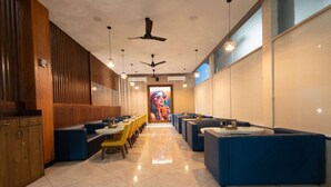 Un restaurante con cabinas y mesas, ventiladores de techo y un gran mural en la pared de fondo.