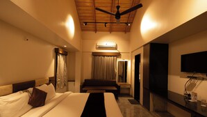 Una habitación de hotel con cama, escritorio, televisor y aire acondicionado.