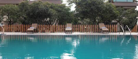 A swimming pool with lounge chairs and a wooden fence.