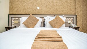 A hotel room with a large bed, two nightstands, a telephone, and a textured wall. - Astorian Grand Hotel (Naivasha)