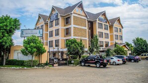 A hotel with a symmetrical facade, multiple windows, and a sign indicating it is the Astorian Birding Hotel. - Astorian Grand Hotel (Naivasha)