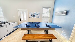 A dining area with a blue table, black chairs, and a wooden bench. - Modern 6 Bedroom House with Tons of Games, BBQ, 2 85" TVs and Surround Sound! (Houston)