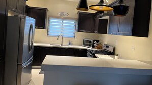 Una cucina moderna con mobili in legno scuro, elettrodomestici in acciaio inossidabile, un'isola centrale e luci a sospensione.
