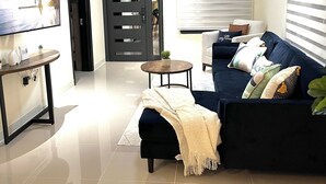 Un soggiorno moderno con un divano blu scuro, un tavolino, una televisione e una ventola a soffitto.