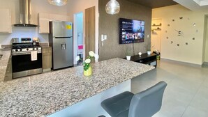 Une cuisine moderne dotée de plans de travail en granit, d’appareils électroménagers en acier inoxydable et de luminaires suspendus.