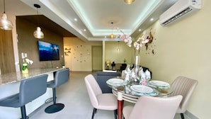 Un espace repas moderne avec une table ronde, des sièges de bar et un téléviseur fixé au mur.
