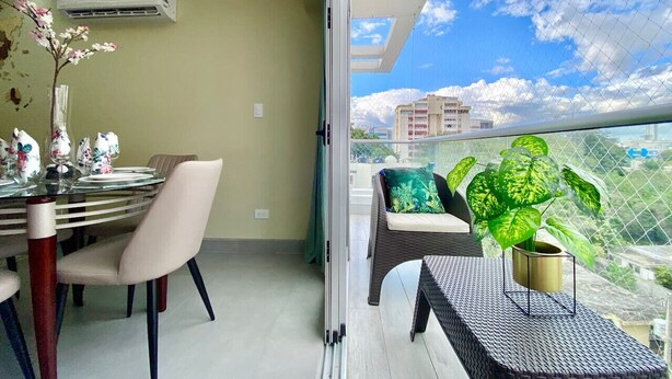 Un balcon avec une table à manger, des chaises et un pot de fleurs.