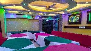 A room with multiple beds, each covered with a green and white bedspread, and a red couch. - Wood Burn Hotel (Bogra)