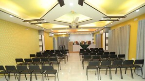 A conference room with rows of chairs facing a stage with a podium. - Wood Burn Hotel (Bogra)