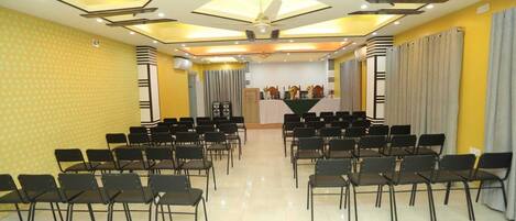 A conference room with rows of chairs facing a stage with a podium.