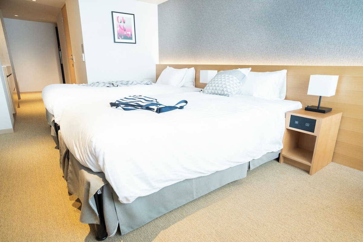 A hotel room with a large bed, a bedside table with a lamp, and a wall-mounted artwork.