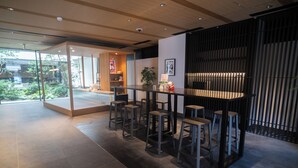 A modern bar area with stools, a counter, and a view of greenery outside. - KABIN Taka (Kyoto)