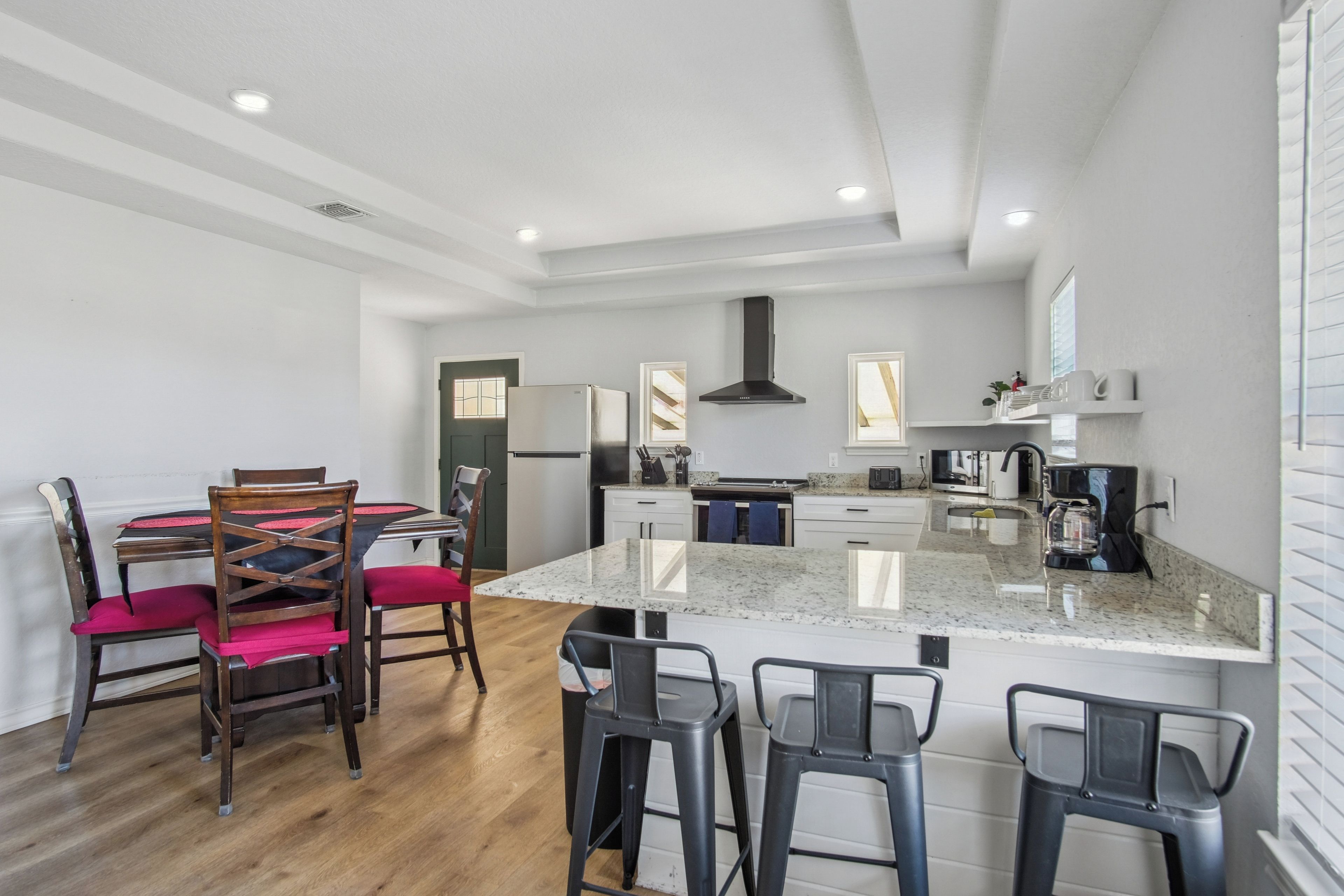 Eine moderne Küche mit Kochinsel, Barhocker und einem Esstisch mit Stühlen.