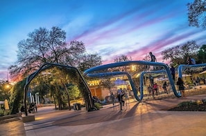 Un espace public extérieur doté de structures architecturales modernes, d’aires de repos et d’arbres.