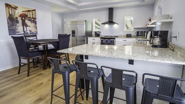 A modern kitchen with a large island, bar stools, and a dining area with chairs.