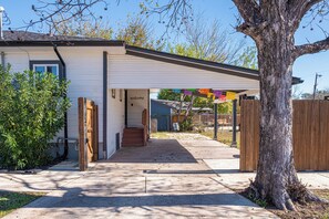 A residential property with a covered entryway, a visible staircase, and a tree in the foreground. - Cozy Downtown Oasis! (San Antonio)