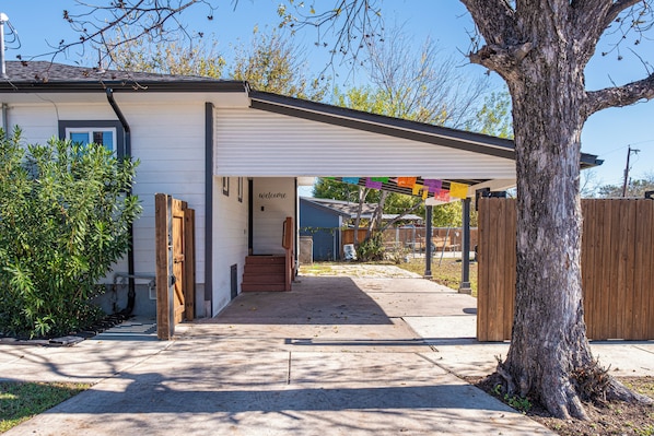 A residential property with a covered entryway, a visible staircase, and a tree in the foreground.