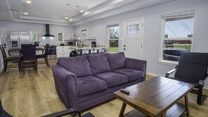 A modern kitchen with a dining area, a purple sofa, and a wooden table.