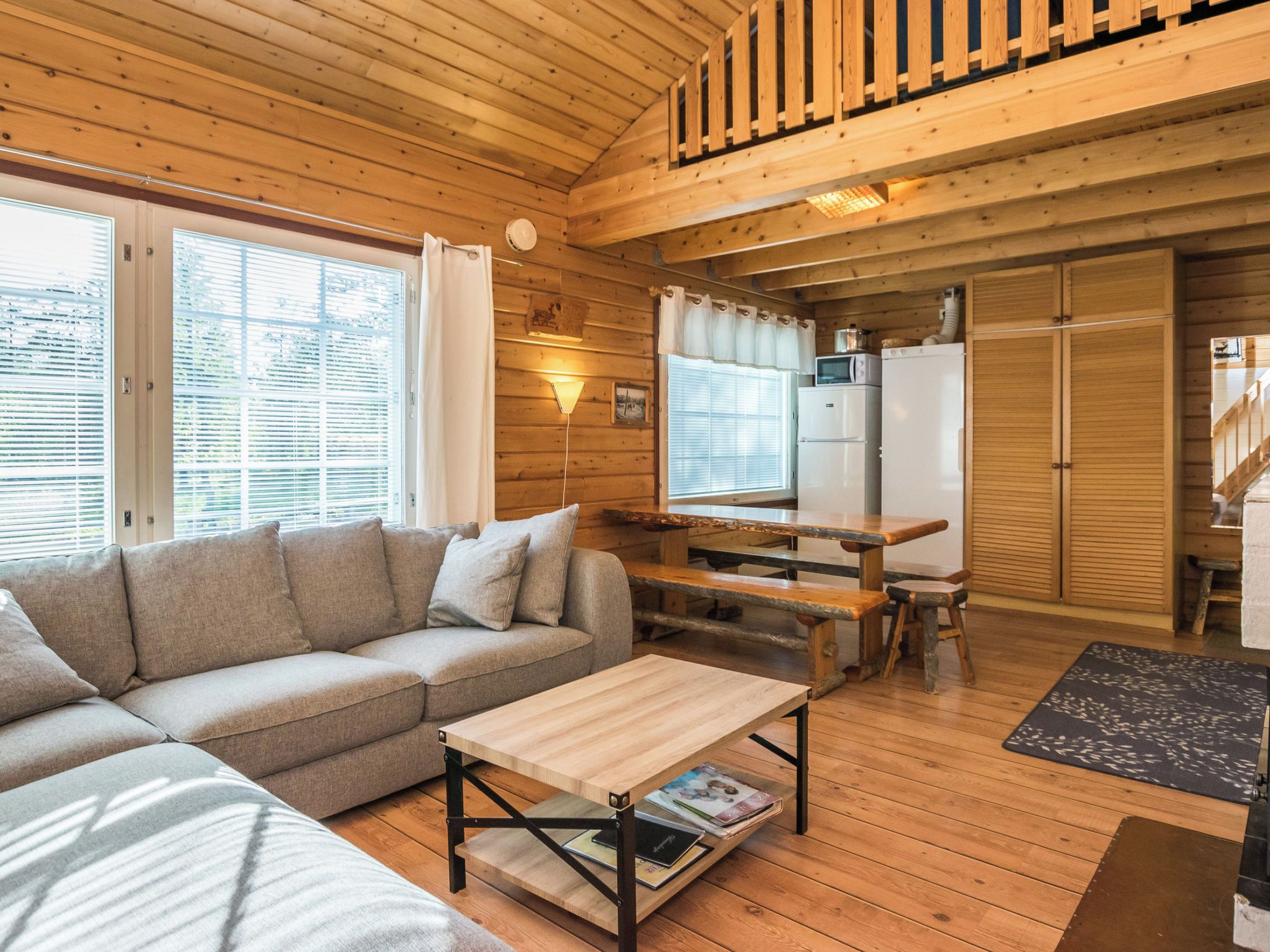 L’intérieur d’un chalet en bois, avec un canapé, une table à manger et un coin cuisine.